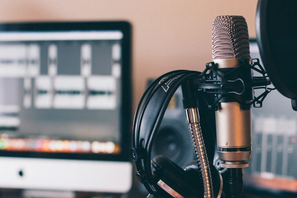 Studio microphone and headphones in front of an editing screen