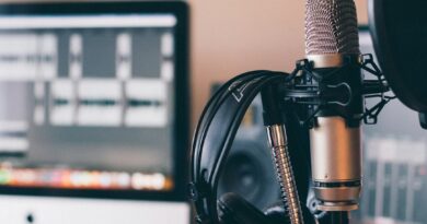 Studio microphone and headphones in front of an editing screen