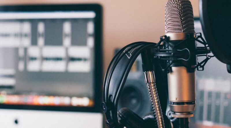 Studio microphone and headphones in front of an editing screen