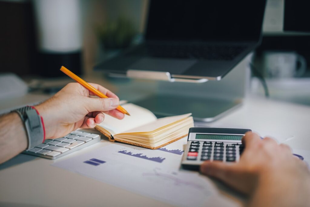 Hands using a calculator beside an open notebook