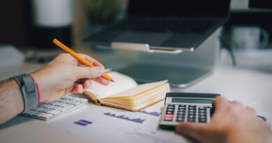 Hands using a calculator beside an open notebook