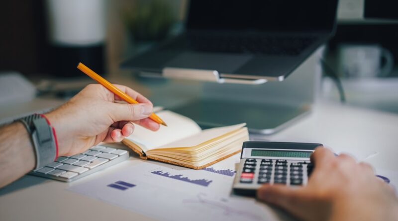 Hands using a calculator beside an open notebook