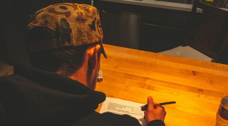 Person writing in a notebook at a wooden desk