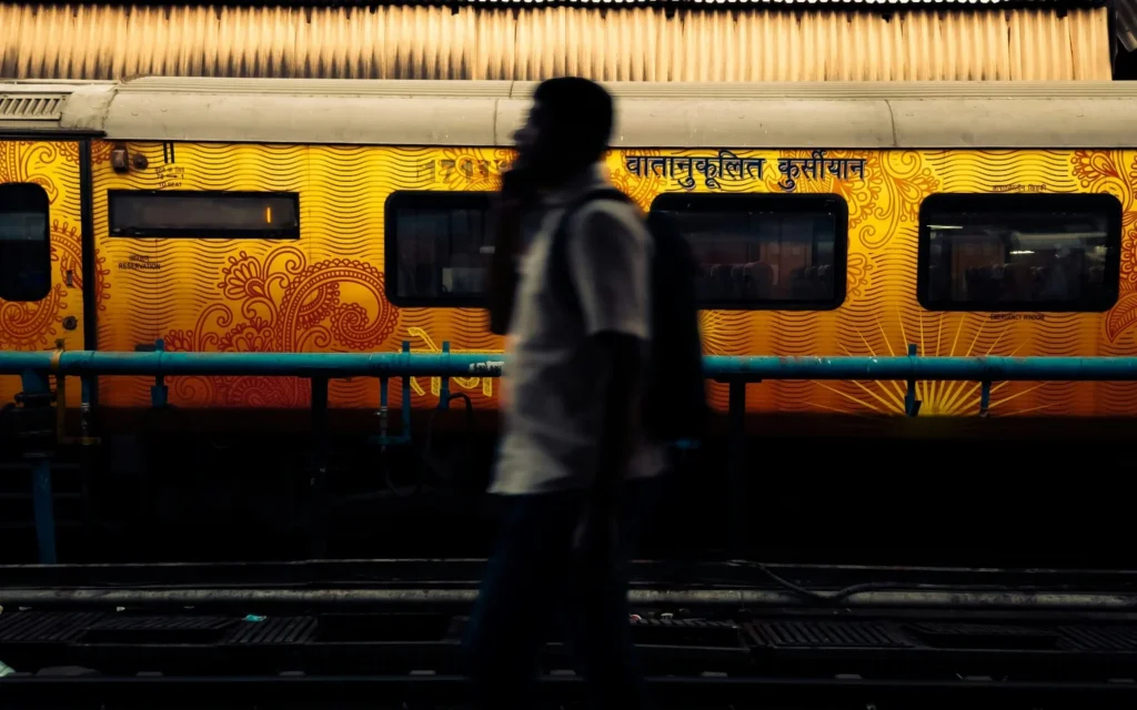 A person standing on a station platform beside a yellow train