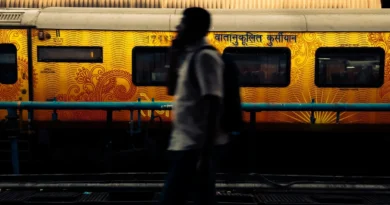 A person standing on a station platform beside a yellow train