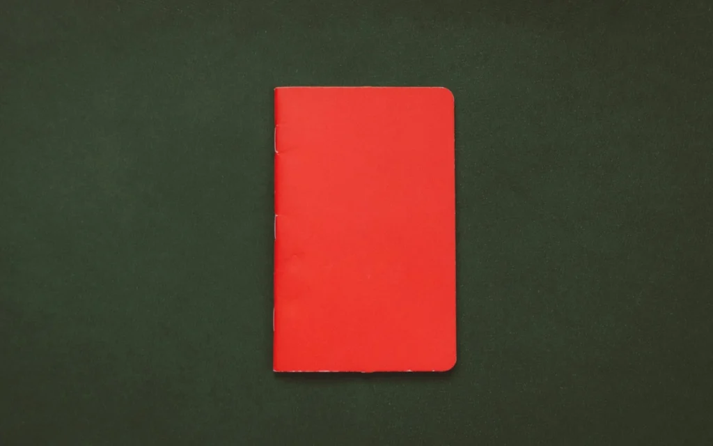 A red notebook on a dark green surface