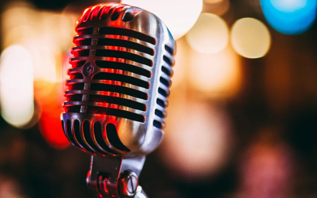 A vintage microphone lit in red against colourful blurred lights